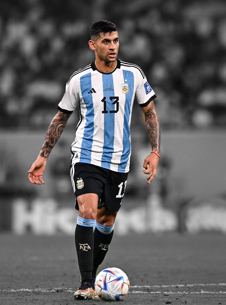 Cristian romero playing in an Argentian shirt wearing number 13, focusing on the ball during a FIFA World Cup match