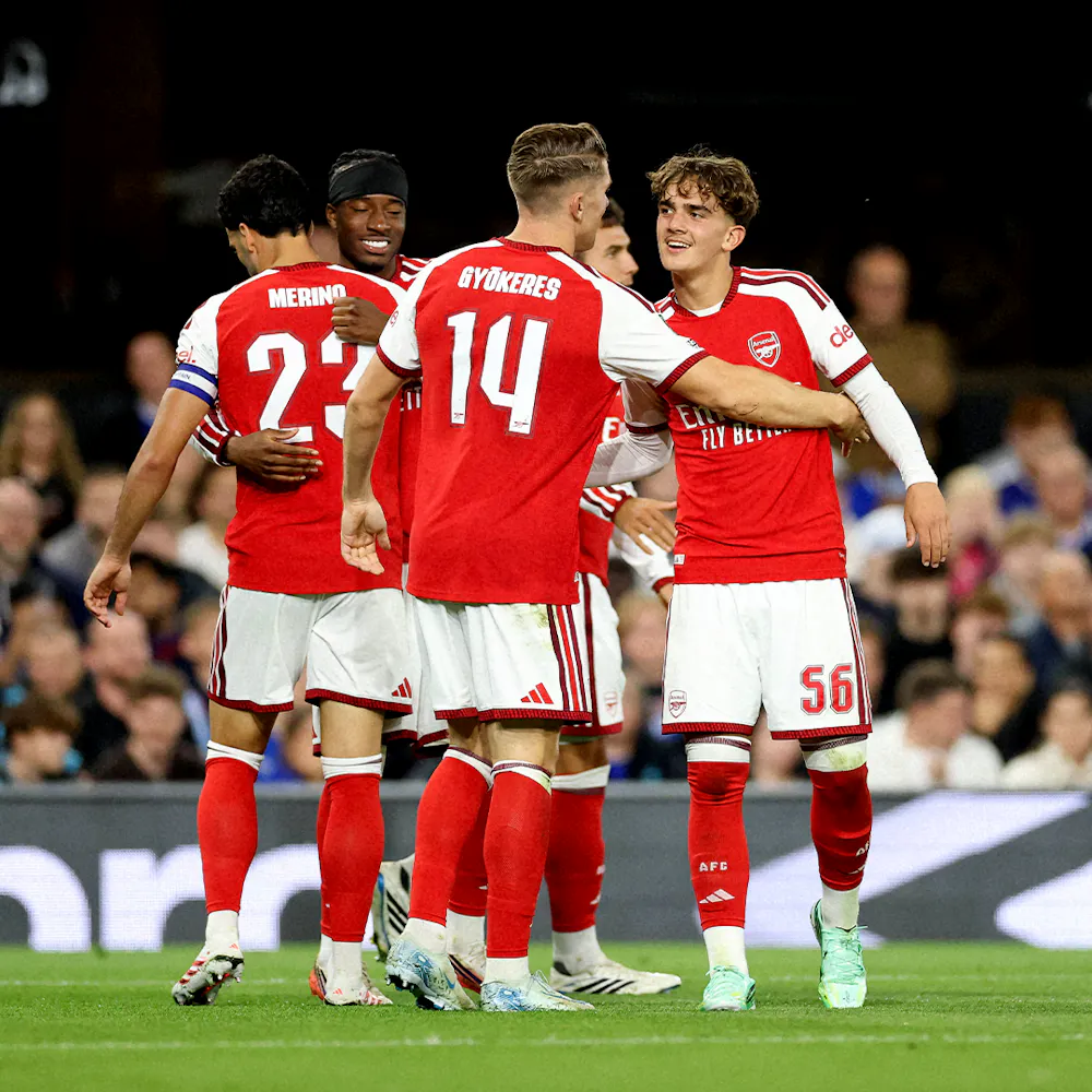 Soccer players in red and white kits celebrating on the field, with arms around each other, during a match.