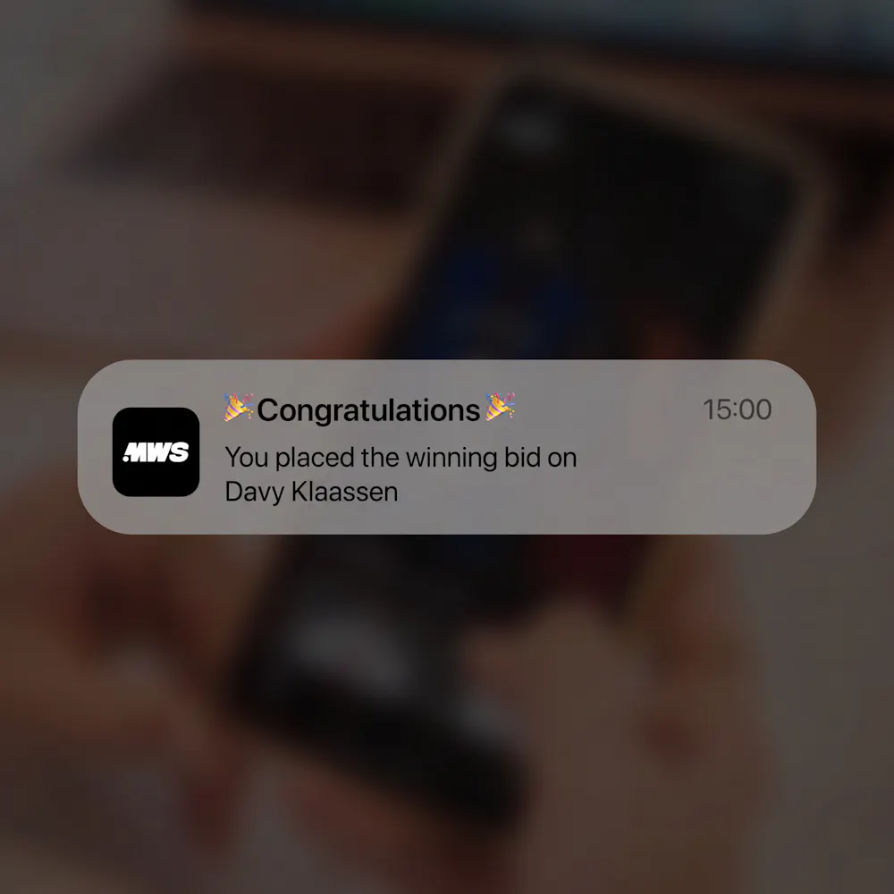 A notification reads, "Congratulations. You placed the winning bid on Davy Klaassen" with a blurred background of a person holding a phone.
