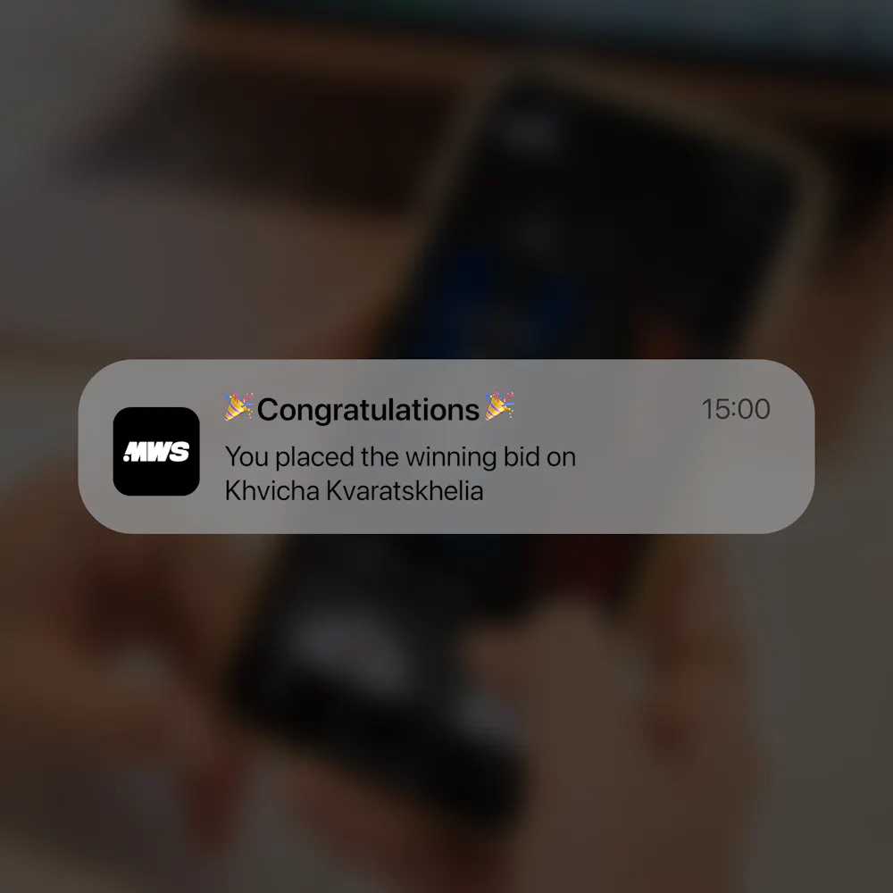 Notification on a phone screen saying, "Congratulations! You placed the winning bid on Khvicha Kvaratskhelia" with a 15:00 timestamp.